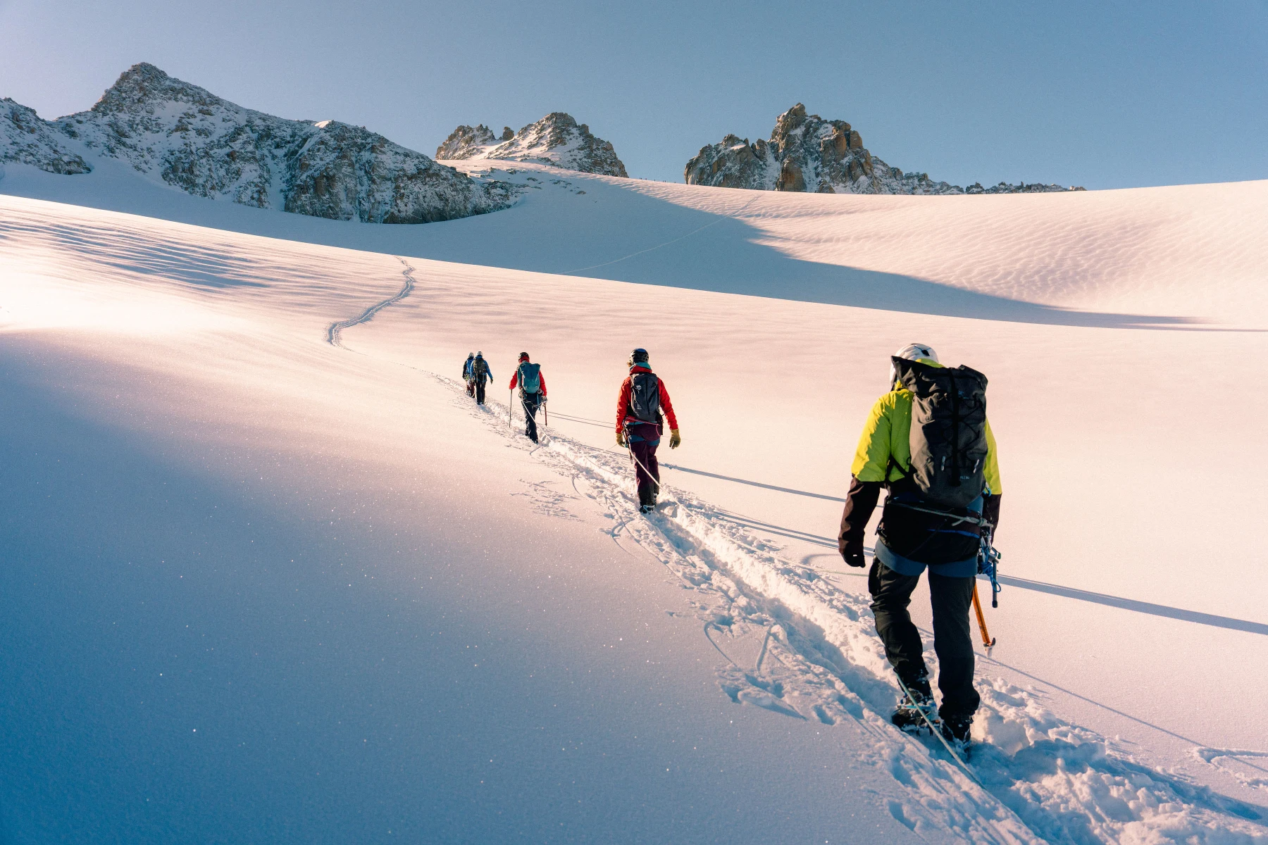 A roped group crossing a glacier toward a snowy ridge